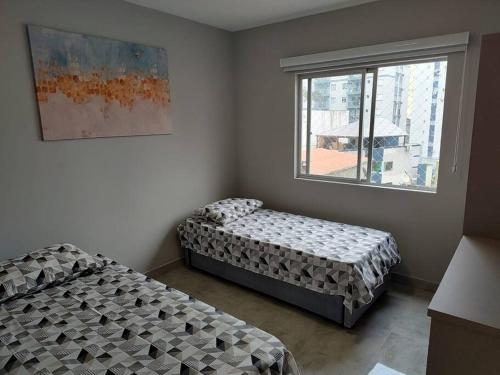 deux lits dans une chambre avec une fenêtre dans l'établissement Amplo apartamento na quadra mar, à Balneário Camboriú