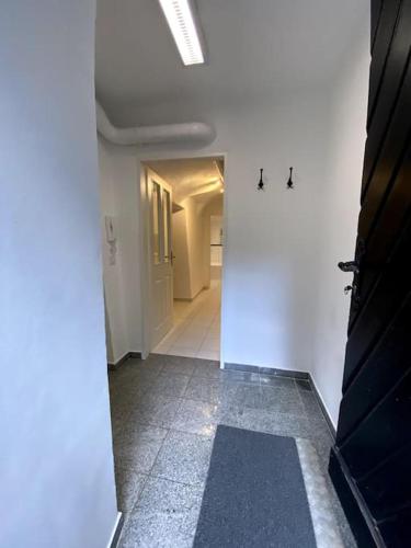 a hallway with white walls and a tile floor at Design Stadthaus Apartment mit privatem Zugang in Hallein