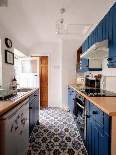 a kitchen with blue cabinets and a tile floor at Cosy Welsh Town Cottage in Brecon
