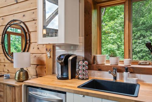 a kitchen with a sink and two windows in a cabin at Le Charme BabyFoot SPA SmarTV Retreat Private domain in Val-des-Lacs