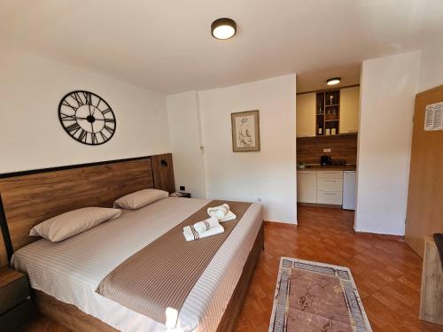a bedroom with a large bed with a clock on the wall at Dom M Apartments in Budva