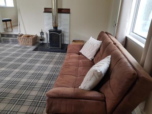 a brown couch with two pillows in a living room at Studio cottage in Tummel Bridge