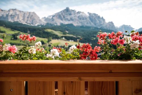 a bunch of flowers on a wooden table with mountains in the background at Hotel Antines in La Villa