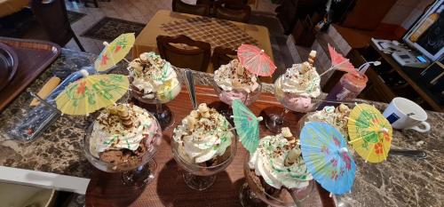 a table topped with ice cream sundas with umbrellas at Complex Turistic Caprioara in Baia Mare