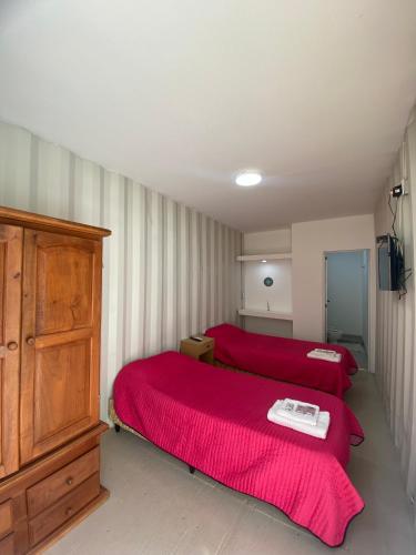 a bedroom with two red beds and a dresser at Hotel en Ruta in Fiambalá