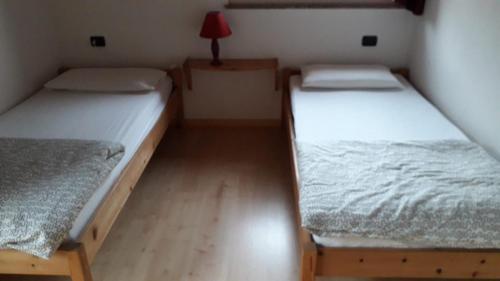 カヴェダーゴにあるMirabel Suite - Lovely Home -のベッドが2つとランプ付きのテーブルがある部屋