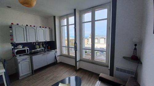 une cuisine avec des placards blancs et une grande fenêtre dans l'établissement Joli Studio vue mer 200 m de la plage, à Pléneuf-Val-André