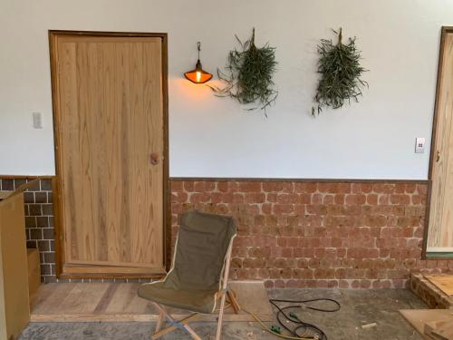 a room with a chair and two plants on the wall at 'Yamaneko Hotel 'Saunas, Serenity & Feline Friends in Miyoshi