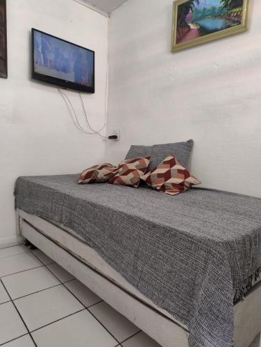 a bedroom with a bed with a tv on the wall at Kitnet aconchegante in Olinda