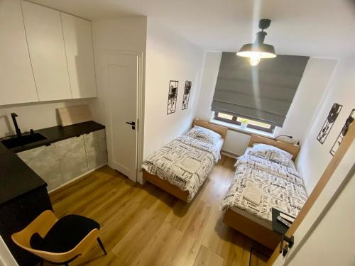 a small room with two beds and a window at Miejska Stodoła in Biała Podlaska