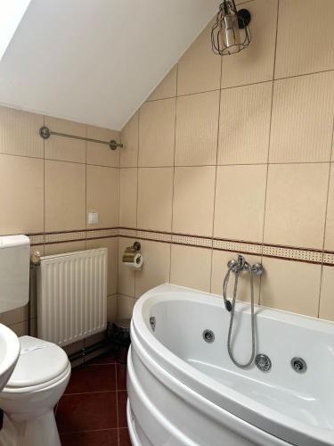 a bathroom with a white tub and a toilet at Pensiunea Boema in Lancrăm