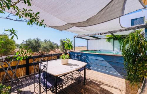 a table and chairs on a deck with a swimming pool at צימר אדיגה in Kafr Kamā