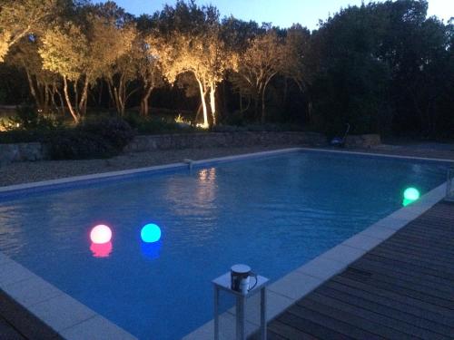 a swimming pool with lights in the water at night at B&B Le Mas Des Chenes in Vacquières