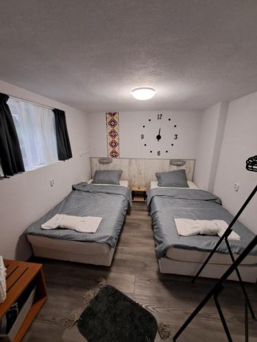 a room with three beds and a clock on the wall at Къща за гости Съкровище in Panagyurishte