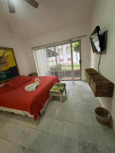 a bedroom with a bed with a red blanket and a television at HAB PTa B ÁREA DE VILLAS DENTRO DEL HOTEL Junto al Krystal EN IXTAPA WIFI 2A 1M Con playa in Ixtapa