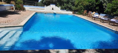a swimming pool with blue water and chairs and chairs at Tapada da Rabela - Reserva Natural in Marvão