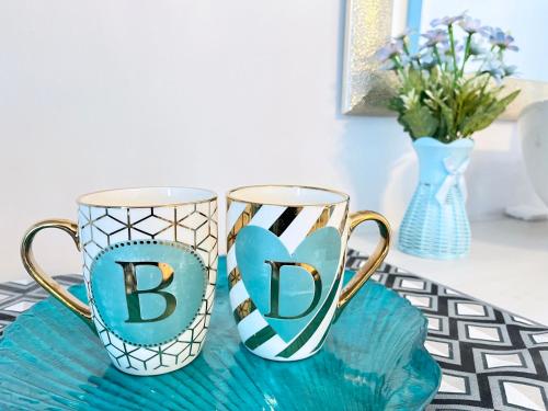 two mugs with the letters bc on top of a table at Blue Diamond Staycation beside Enchanted Kingdom in Santa Rosa Laguna in Santa Rosa