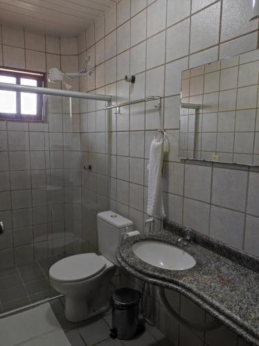 a bathroom with a toilet and a sink and a mirror at Pousada Encantos da Natureza in Praia do Frances