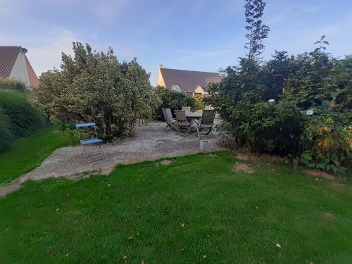 a backyard with a table and chairs in the grass at Les grandes Masures B&B in Varengeville-sur-Mer