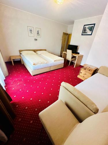 a hotel room with a bed and a red carpet at Gasthof Residence Brugghof & Erlhof in Campo Tures