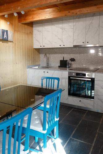 a kitchen with blue chairs and a table and a stove at Casa de Pombares in Veigas
