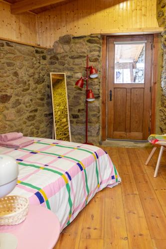 a bedroom with a bed and a stone wall at Casa de Pombares in Veigas