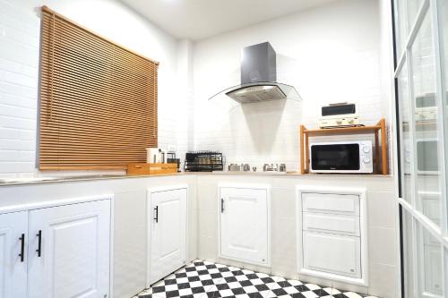 a kitchen with white cabinets and a black and white checkered floor at Good Day House บ้านพักนครพนม ริมแม่น้ำโขง in Nakhon Phanom