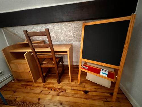a chair sitting next to a desk and a chalkboard at Gîte de la petite Reine in Champagney