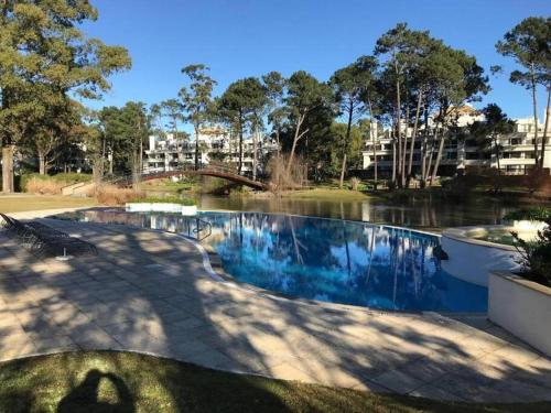 a swimming pool in a park next to a body of water at Departamento en Green Park in Punta del Este