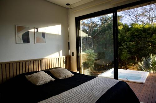 a bedroom with a bed and a large window with a tub at Casa Nengueta - Lapinha da Serra in Santana do Riacho