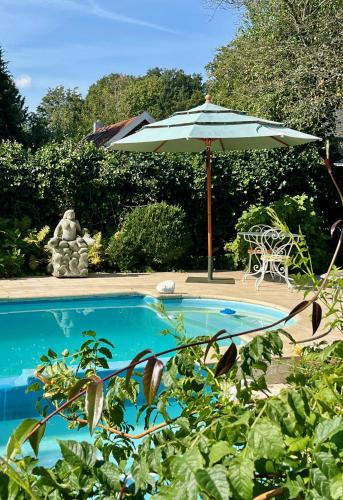 a swimming pool with an umbrella and a table and chair at The Pool House in Den Dolder