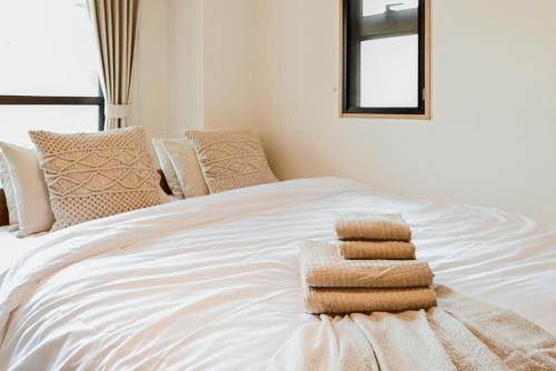 a white bed with three folded towels on it at New! Japandi 3 1BR in Prime Location-1 min to STN in Hakata