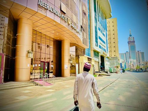 a man walking down a street in front of a building at فندق عبير الفضيلة in Al Masfalah
