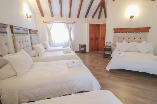 a hotel room with two beds and a window at Hotel las Palmas in Villa de Leyva