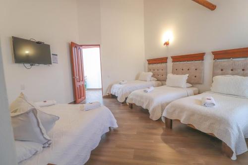 a room with four beds and a flat screen tv at Hotel las Palmas in Villa de Leyva