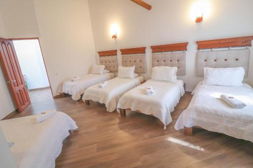 a room with four beds with white sheets at Hotel las Palmas in Villa de Leyva