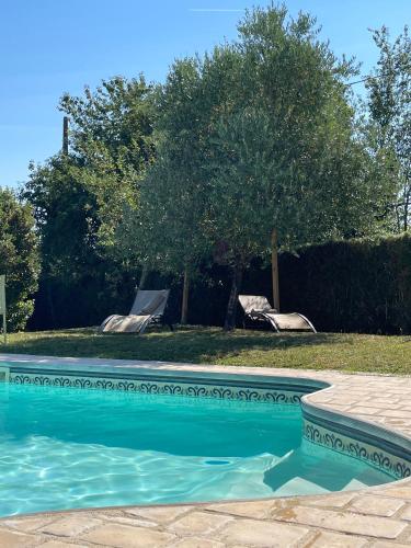 une piscine avec deux chaises et un arbre dans l'établissement Chambre, sauna, piscine à la campagne, à Léguillac de Cercles
