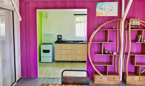 a kitchen with a purple wall and a mirror at The Rusty Pelican in La Gaulette