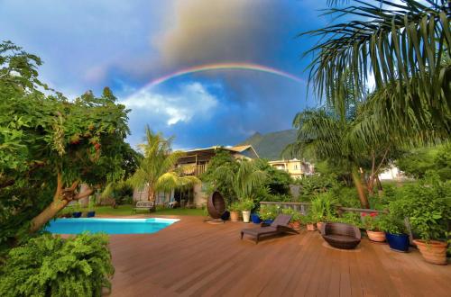 a rainbow in the sky over a house with a pool at The Rusty Pelican in La Gaulette