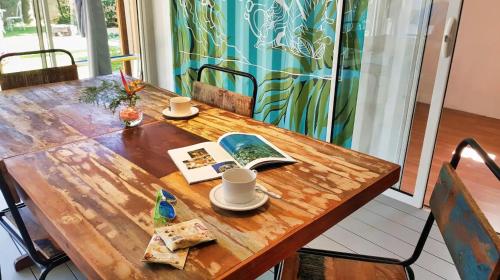 a wooden table with two cups and a book on it at The Rusty Pelican in La Gaulette