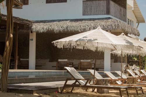 a group of chairs and an umbrella next to a pool at Villa Praia - La Villa Group in Jericoacoara