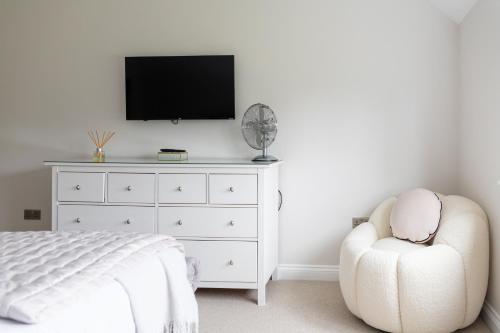 a bedroom with a white dresser and a tv at The Luxury House in Swanland