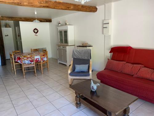 un salon avec un canapé rouge et une table dans l'établissement GITE LA COMBE pour les amateurs de nature, à Saint-Étienne-du-Bois