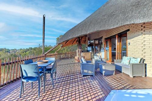 a deck with a table and chairs and a thatch roof at Thula-Thula Private Game Lodge Mabalingwe in Bela-Bela
