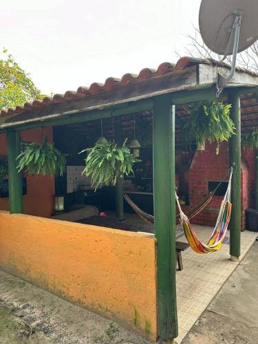 a porch with a hammock and two potted plants at Pousada Aconchego do Rosa - Centrinho do Rosa in Praia do Rosa