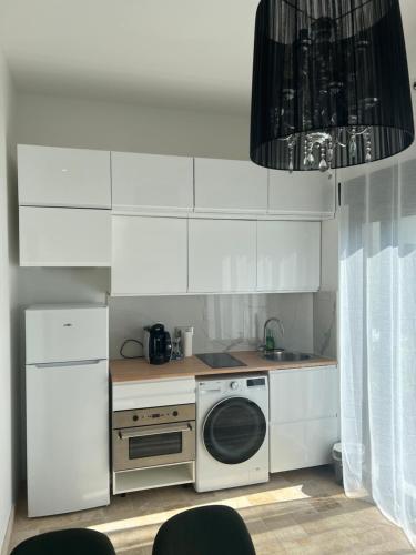 Il comprend une cuisine blanche équipée d'une cuisinière et d'un four micro-ondes. dans l'établissement Studio Appart 35m, à Rosny-sous-Bois