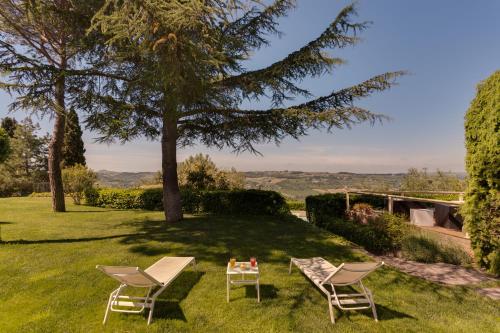 two chairs and a table in the grass at Villa I Barronci Resort & Spa in San Casciano in Val di Pesa