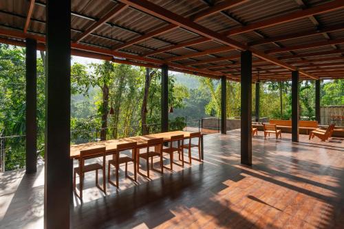 a pavilion with tables and benches on a deck with trees at River Pavilion, Kitulgala in Yatiyantota