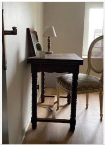 une table en bois avec une chaise et une lampe. dans l'établissement Saint Malo centre lambety, à Saint-Malo
