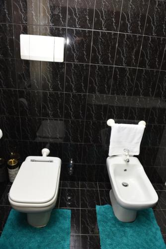 a black tiled bathroom with a toilet and a bidet at Casa Dante in Romano di Lombardia